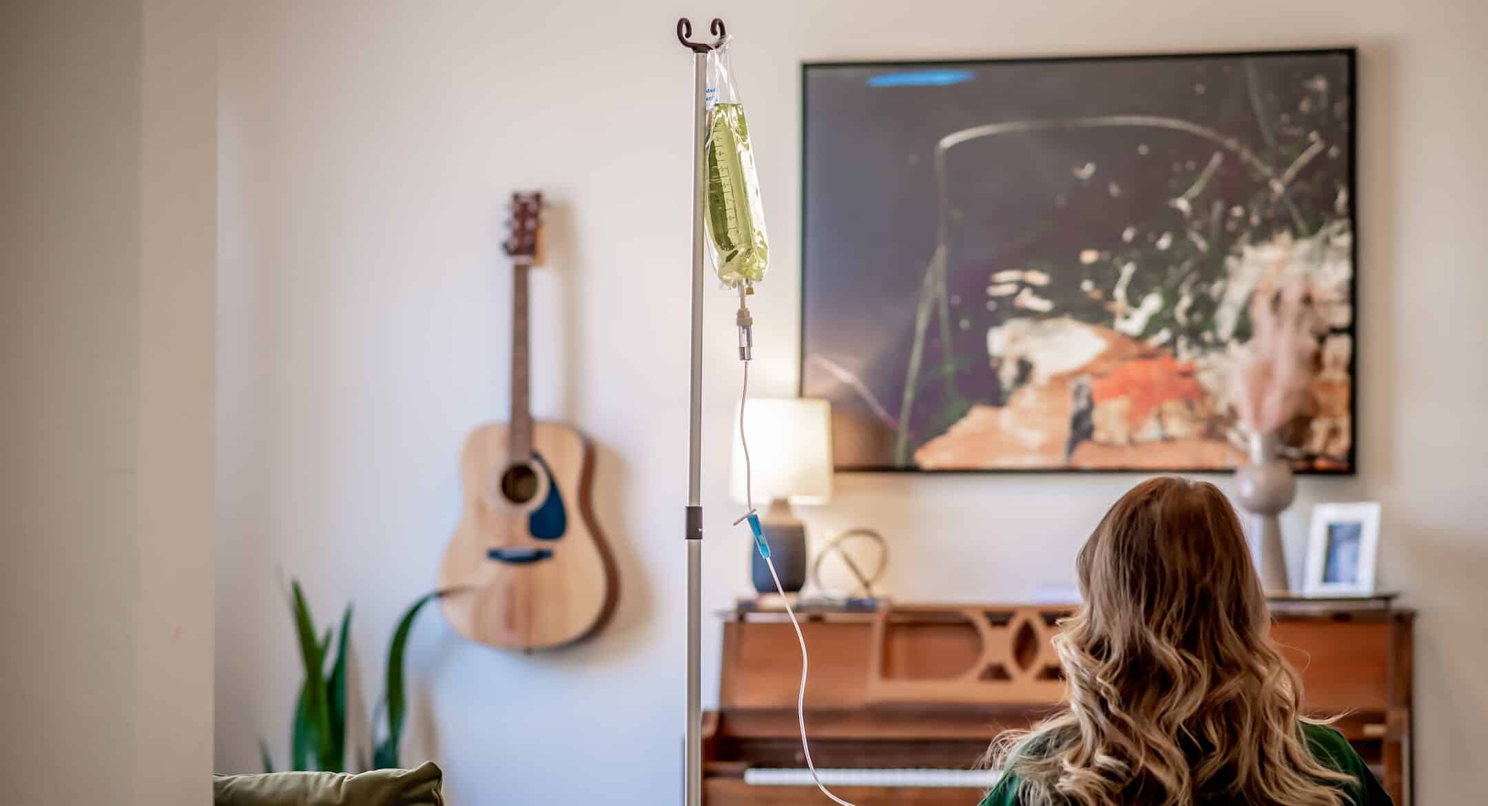Woman receiving IV therapy infusion at home with IV stand